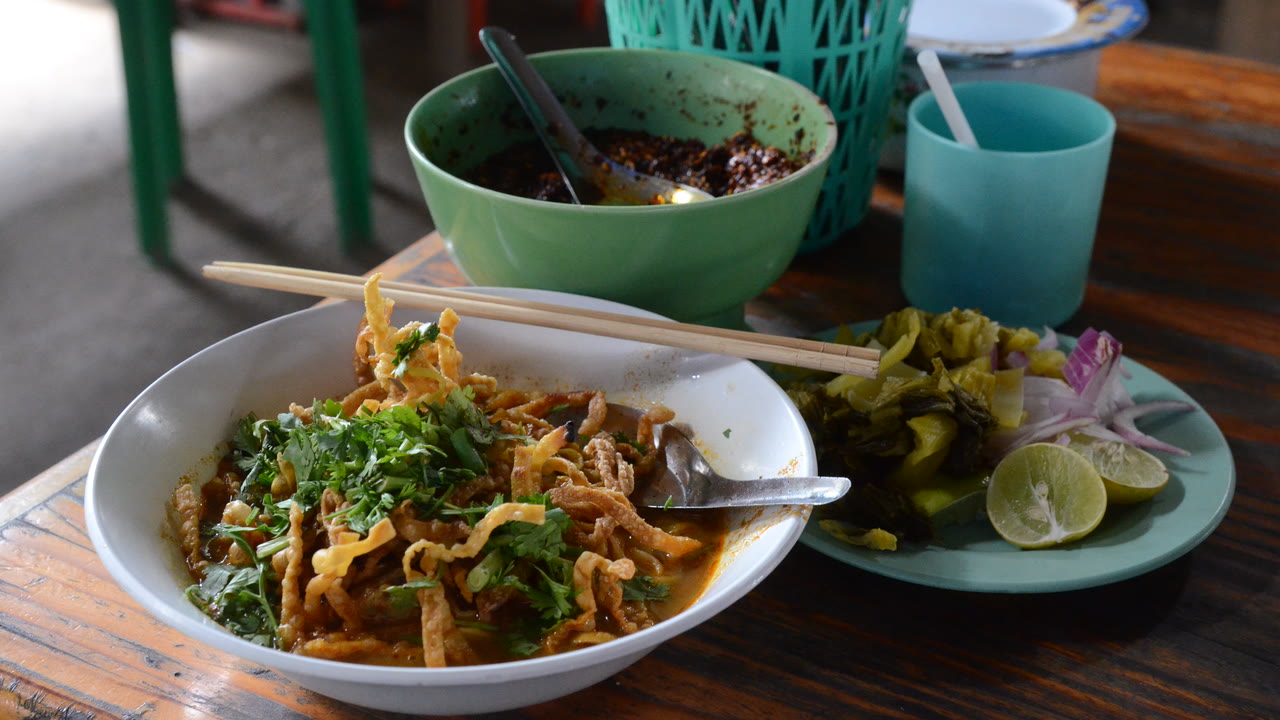 Cuenco de khao soi, sopa de fideos al curri coronada con fideos crujientes, servida con encurtidos y lima en el norte de Tailandia