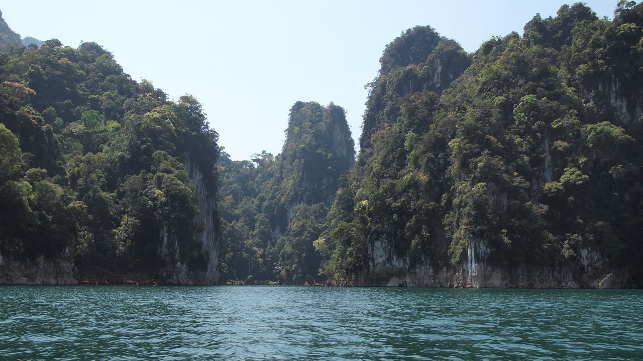 Acantilados de piedra caliza cubiertos de bosque que se elevan sobre las aguas verdes del lago Cheow Lan, en el parque nacional de Khao Sok, Tailandia