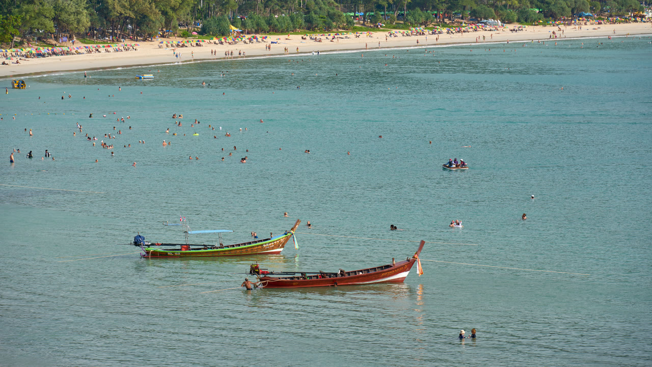 Barcos de cola larga amarrados en aguas turquesas poco profundas frente a Kata Beach, en la costa oeste de Phuket, Tailandia